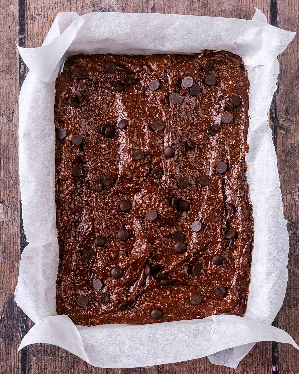 Brownie batter in a lined baking tin.