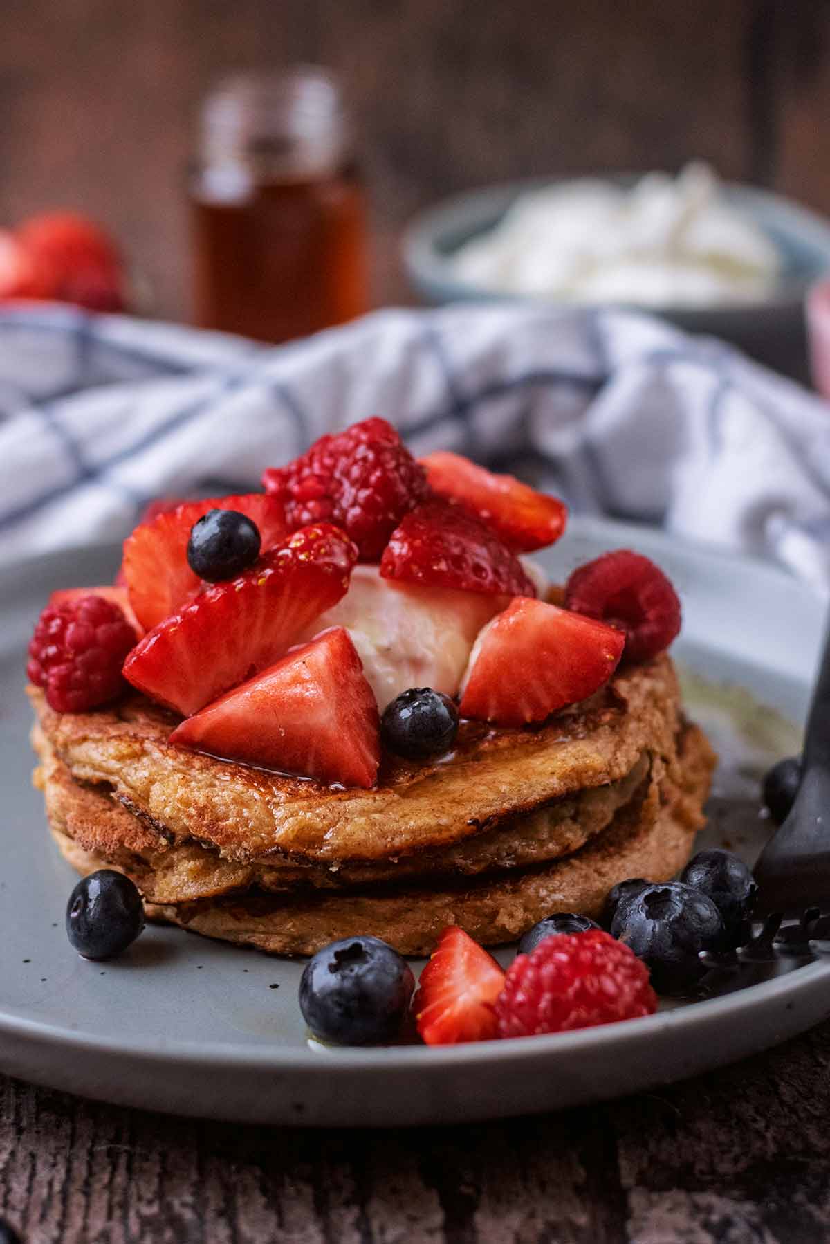 Chopped strawberries, raspberries and blueberies on top of a stack of pancakes.