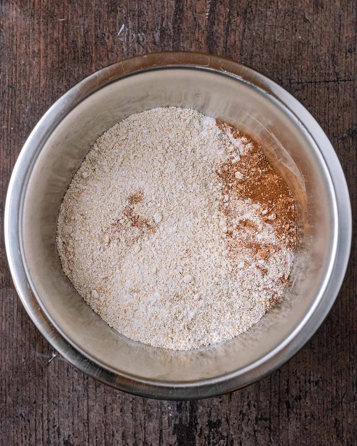 A mixing bowl with oat flour, baking powder and cinnamon in it.