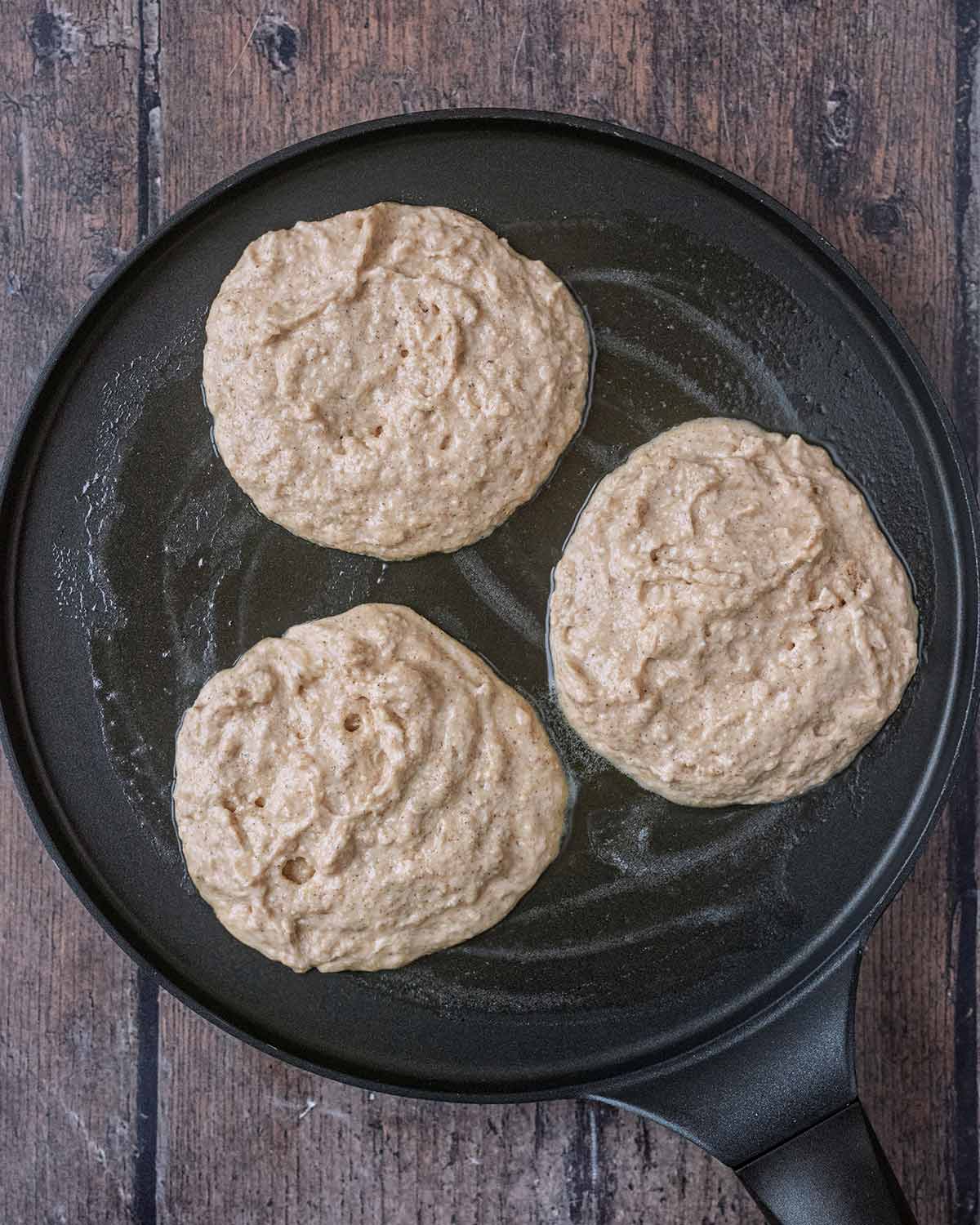 Three rounds of pancake batter on a pancake pan.