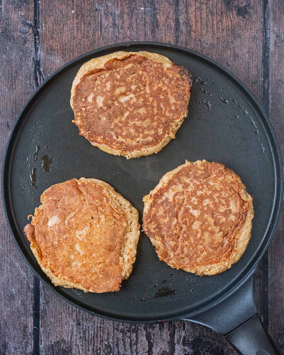 Three cooked pancakes in a pancake pan.