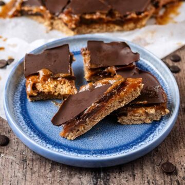 Four pieces of healthy millionaire shortbread on a round blue plate.