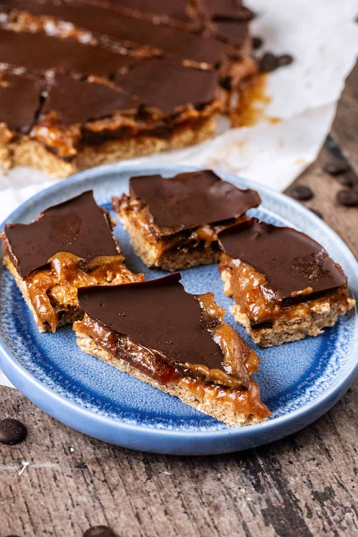 Millionaire's shortbread on a plate in front of more shortbread.