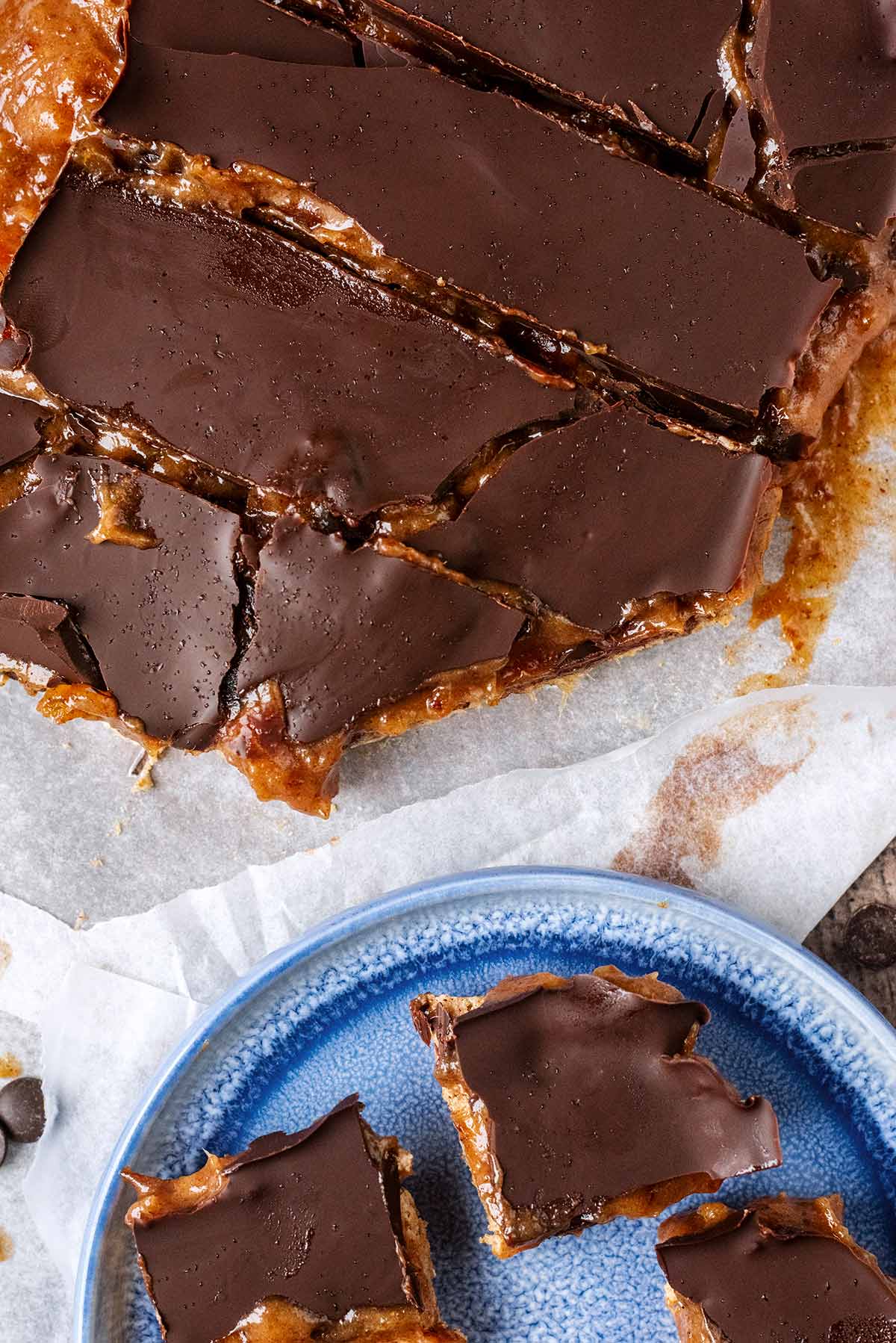 A slab of millionaire's shortbread cut into bars next to plate with some bars on it.