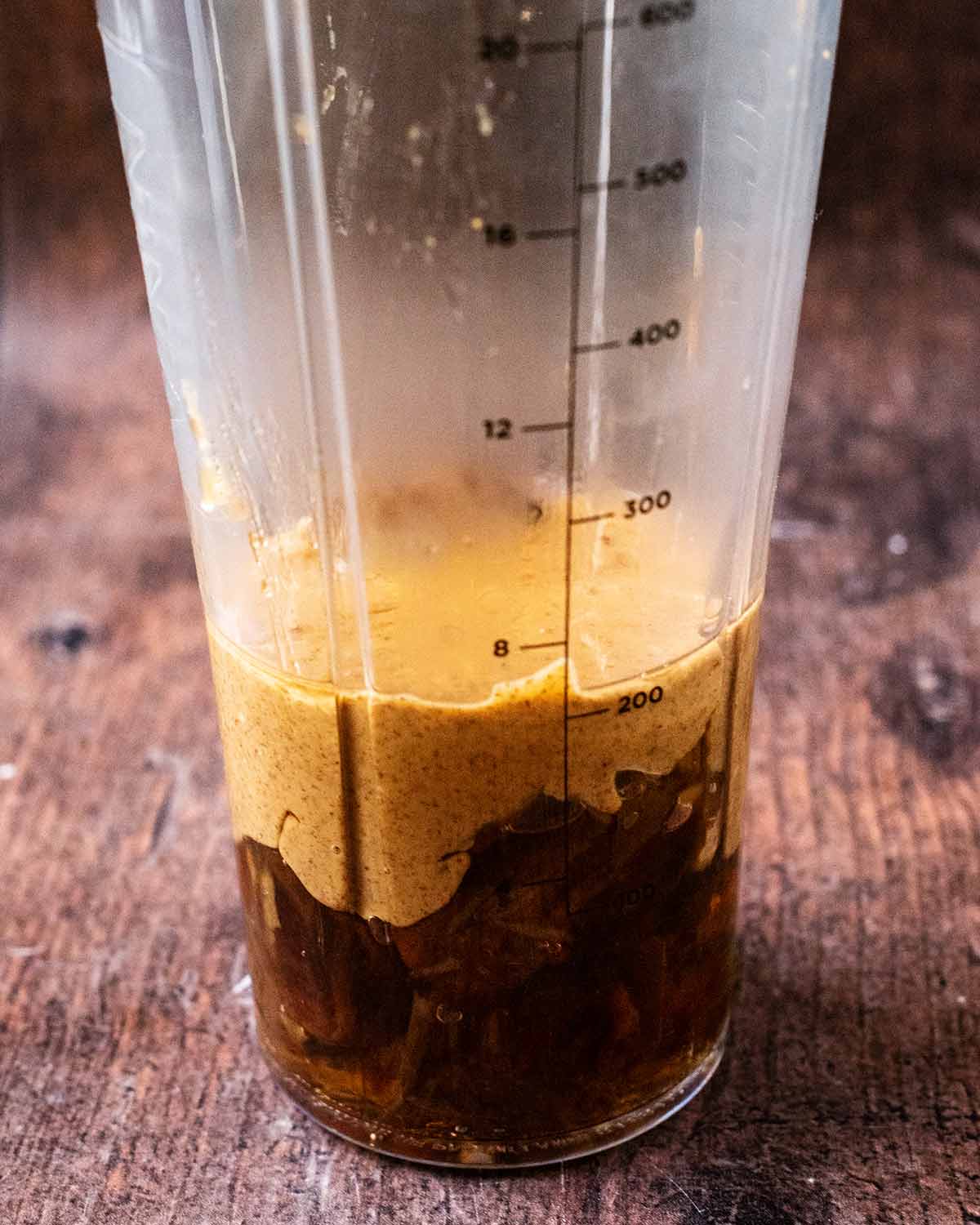 A blender jug with softened dates, almond butter and maple syrup in it.