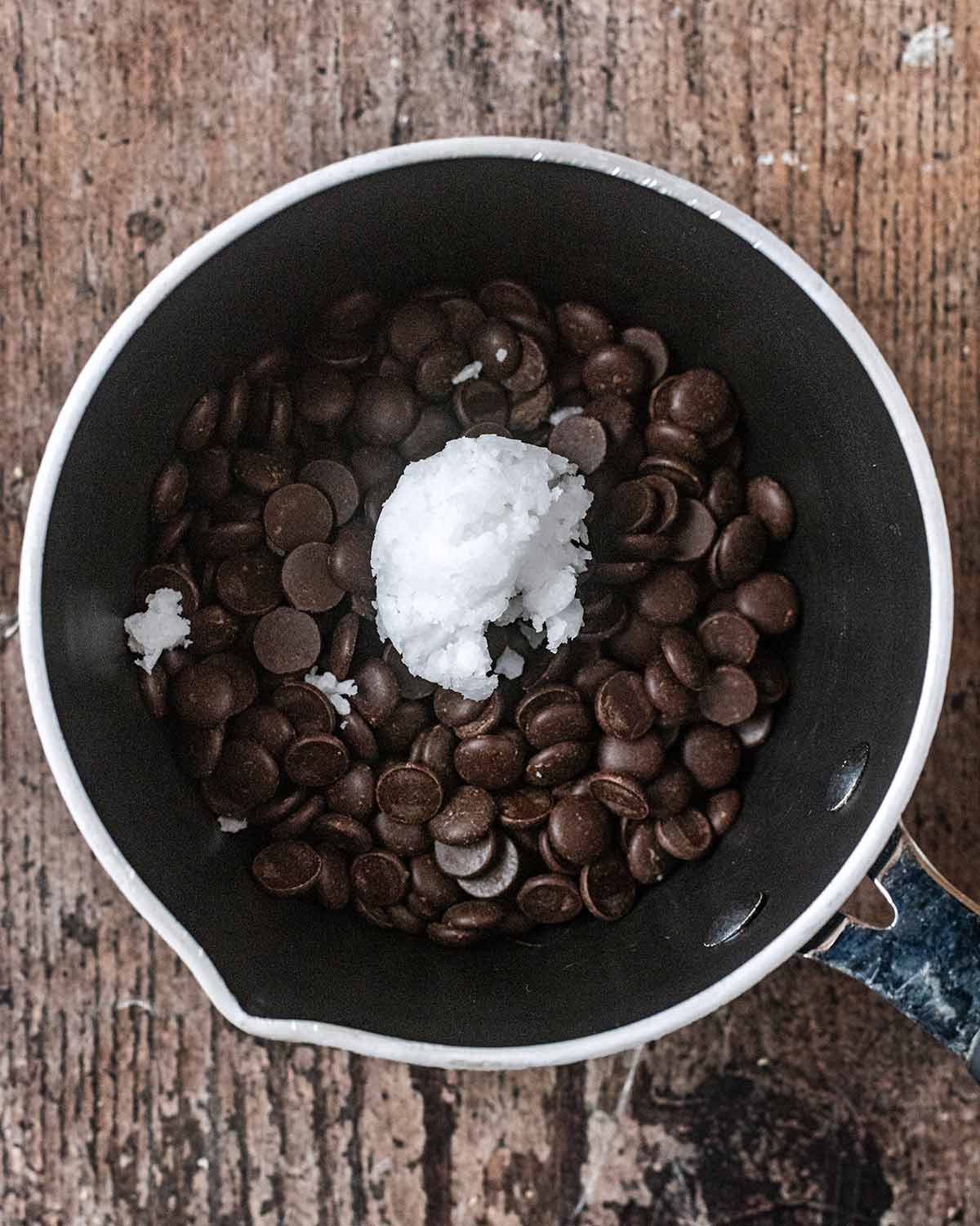 A saucepan with chocolate chips and coconut oil in it.