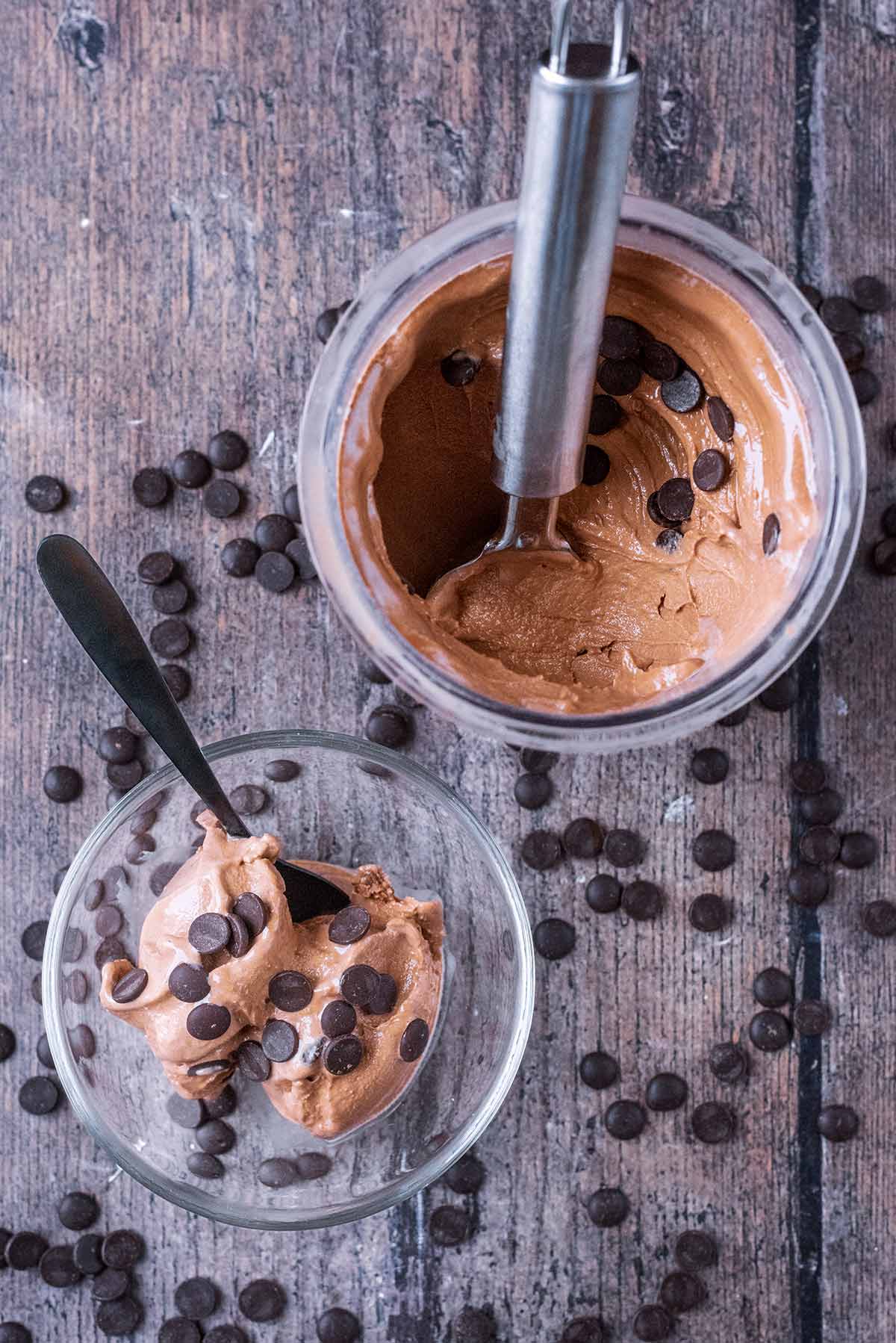 A bowl of chocolate frozen yogurt next to a pint tub of more frozen yogurt.