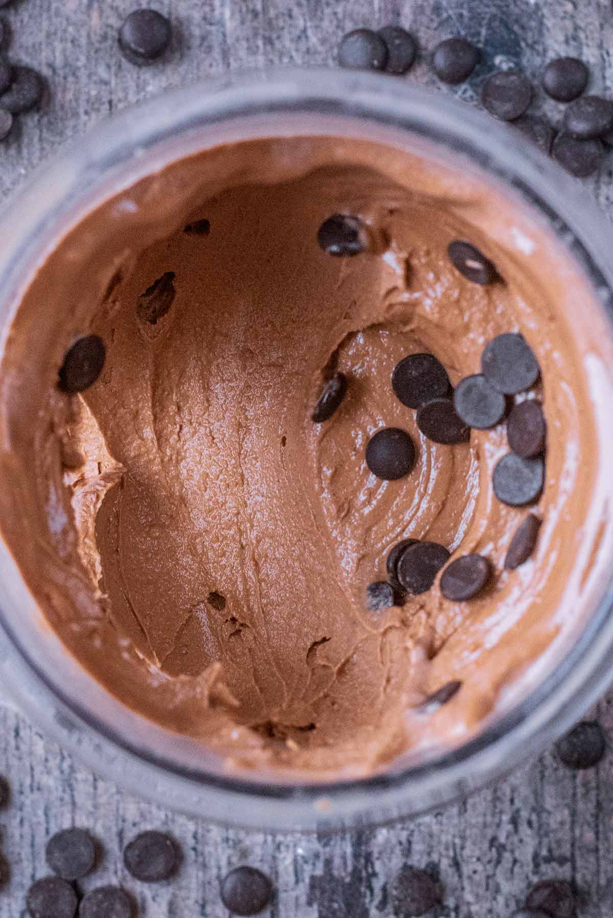 Chocolate frozen yogurt in a tub with a portion scooped out.