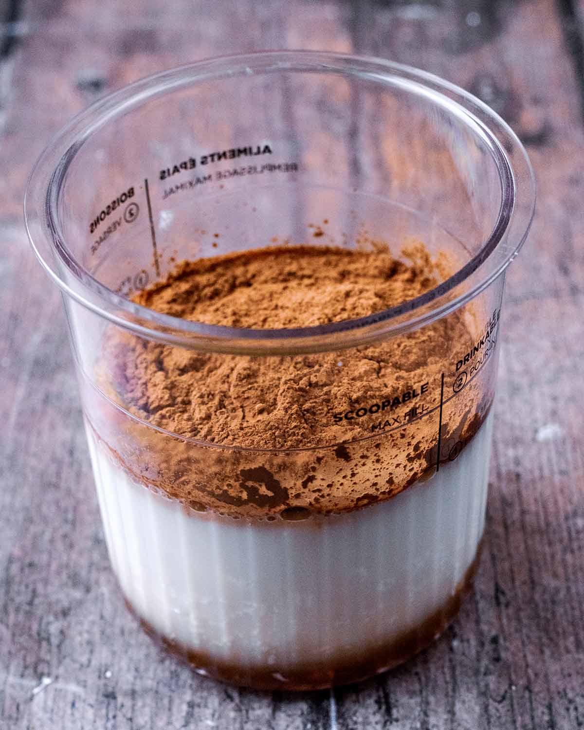 A Creami tub with yogurt, milk, maple syrup and cacao powder.