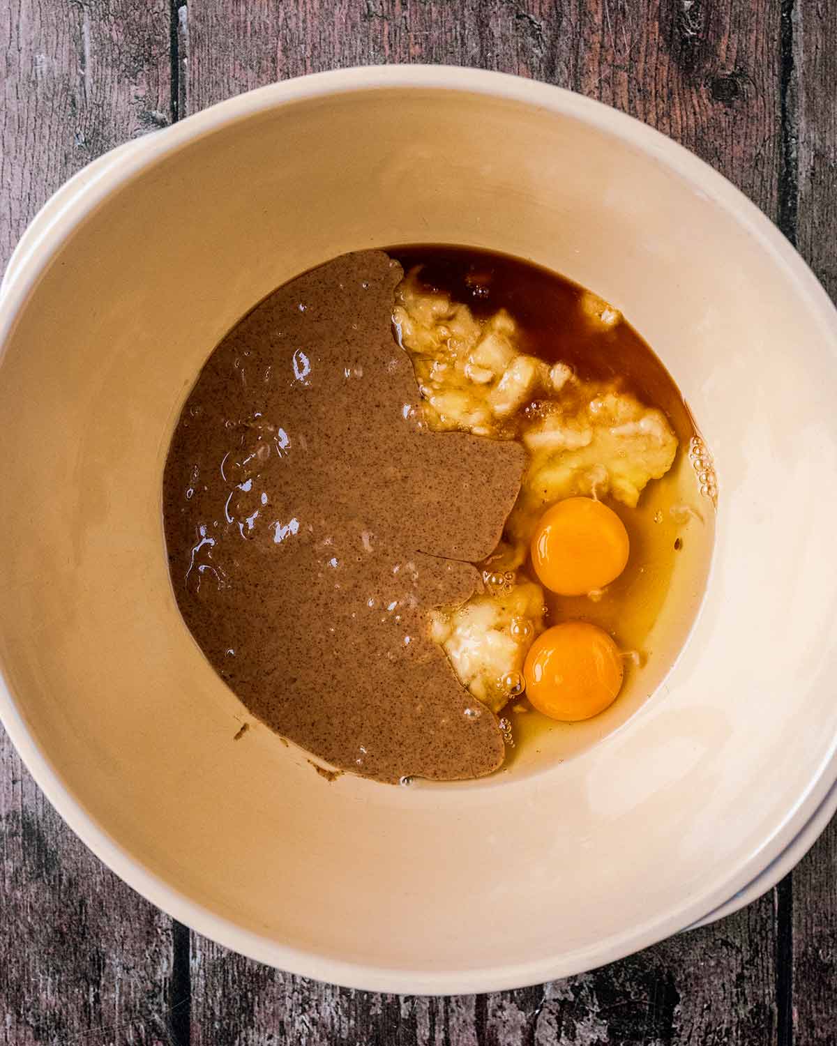 Mashed banana, eggs, maple syrup and nut butter in a large mixing bowl.