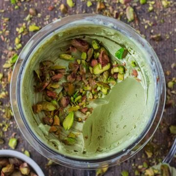 A tub of Ninja Creami Pistachio Ice Cream with a scoop taken out.