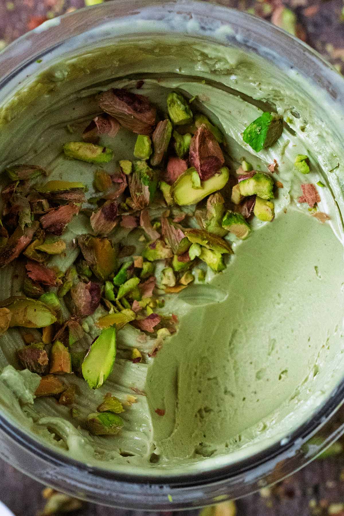 A tub of pistachio ice cream topped with crushed pistachios.