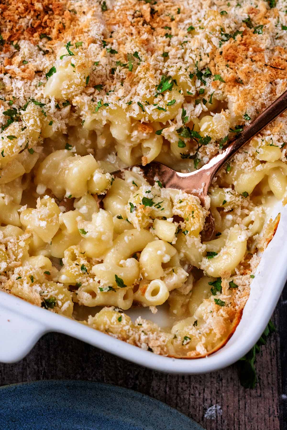 A baking dish of mac and cheese with a spoon having removed a portion.