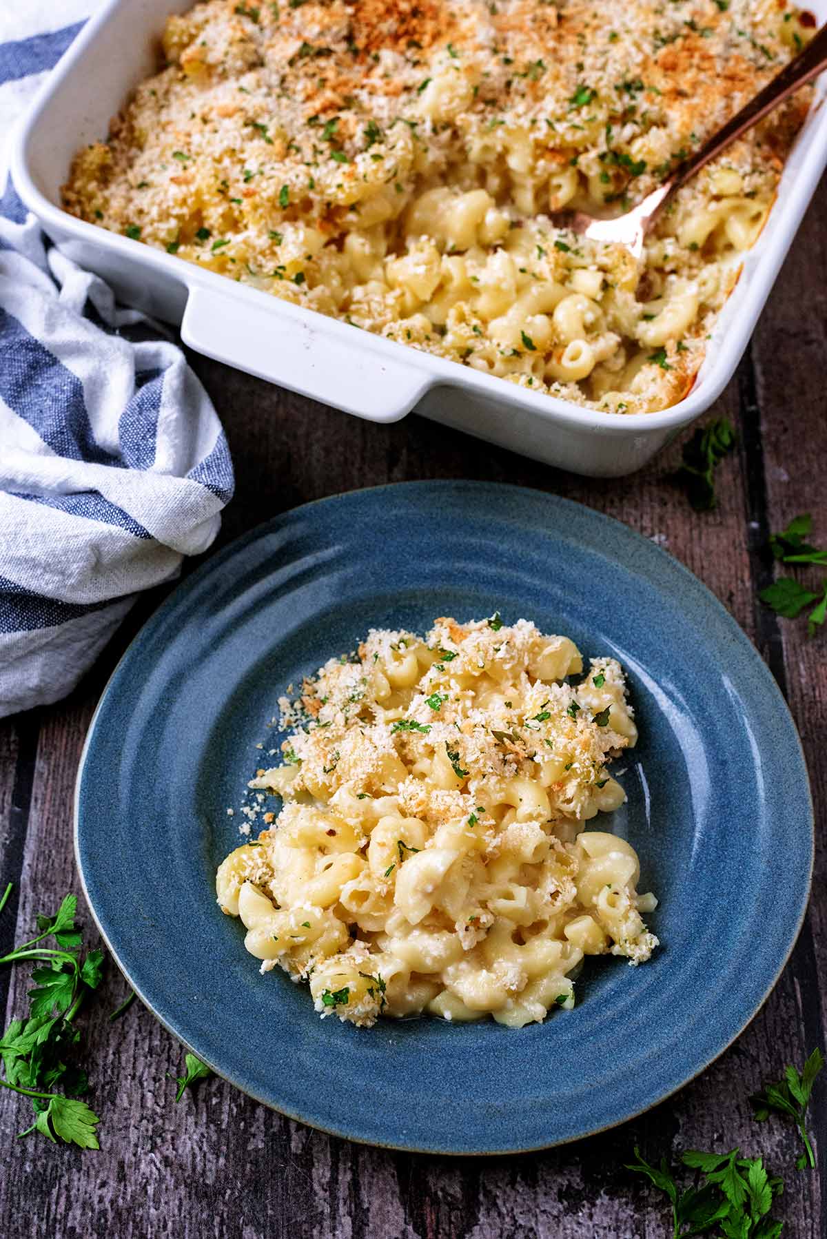 A plate of mac and cheese in front of a baking dish full of more mac and cheese.