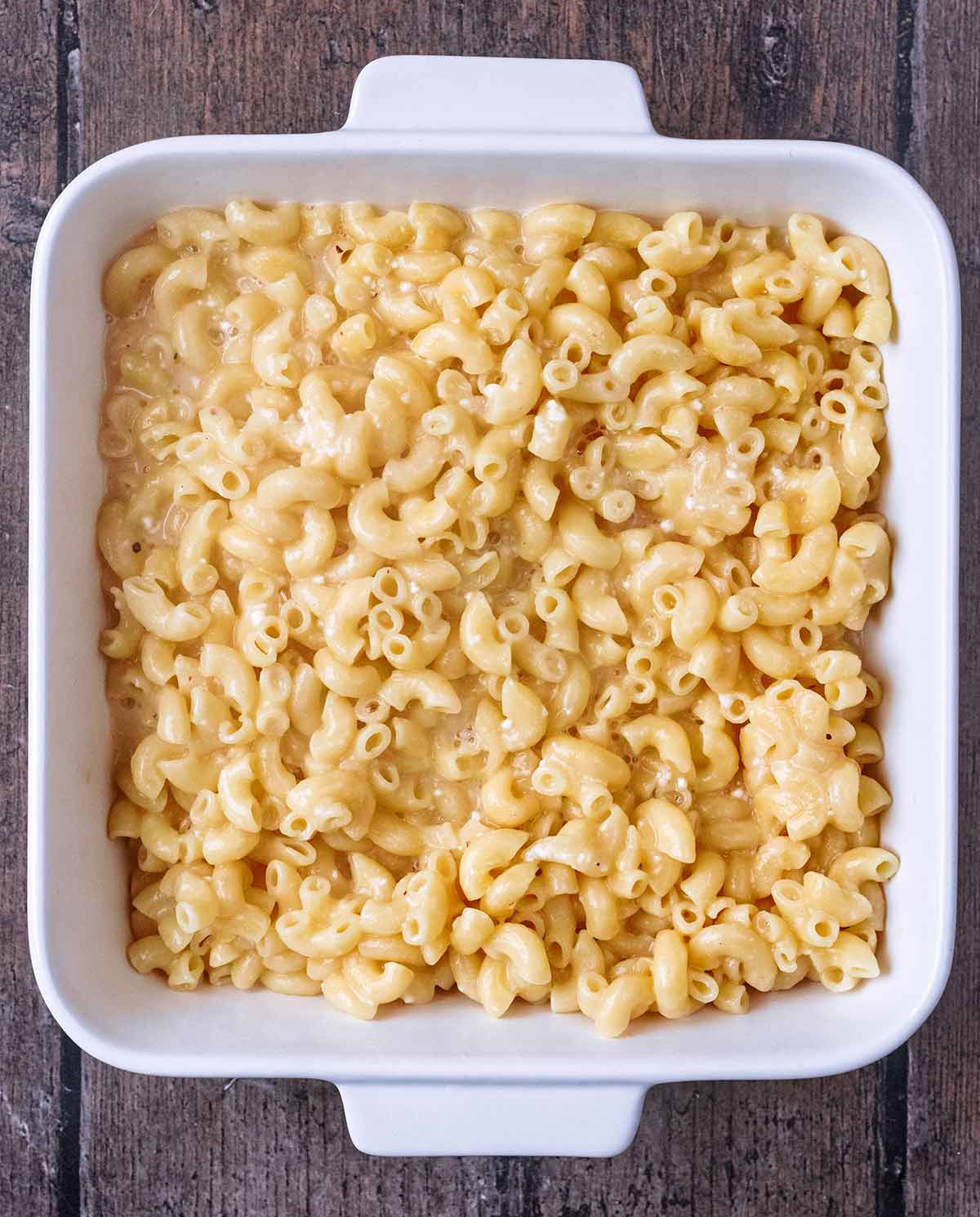 Cooked macaroni and cheese sauce in a square baking dish.