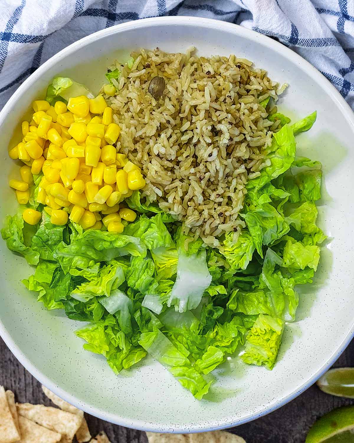 A bowl with chopped lettuce, rice and sweetcorn.