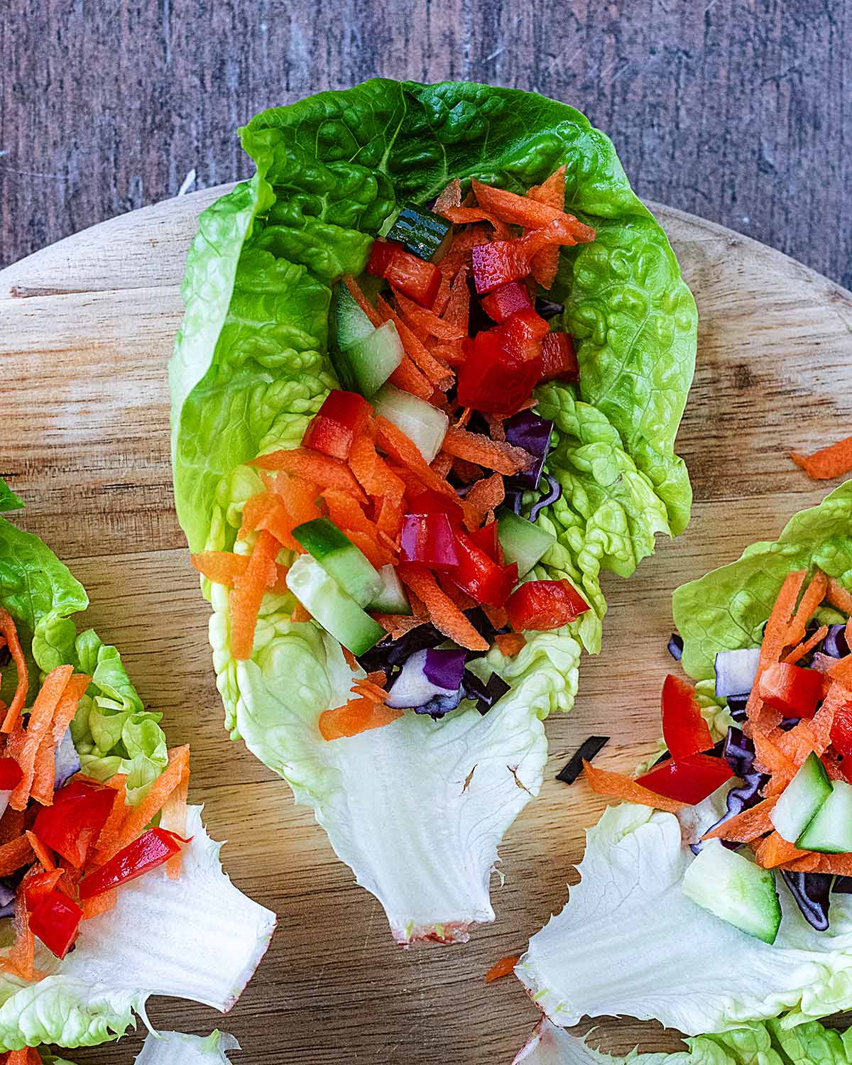 A small lettuce leaf containing diced red pepper, diced cucumber, grated carrot and shredded red cabbage.