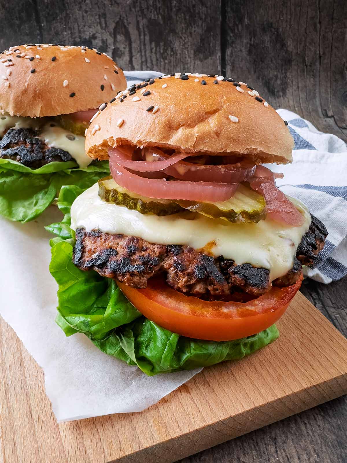 A turkey burger in a bun with cheese and various salad items.