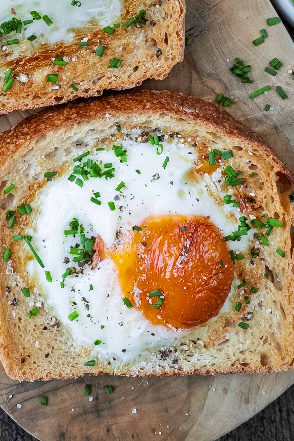 An egg cooked into a slice of bread, topped with chopped chives.