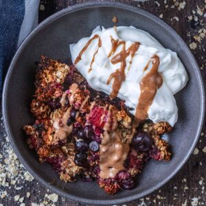 A bowl of breakfast crumble with yogurt and a drizzle of nut butter.