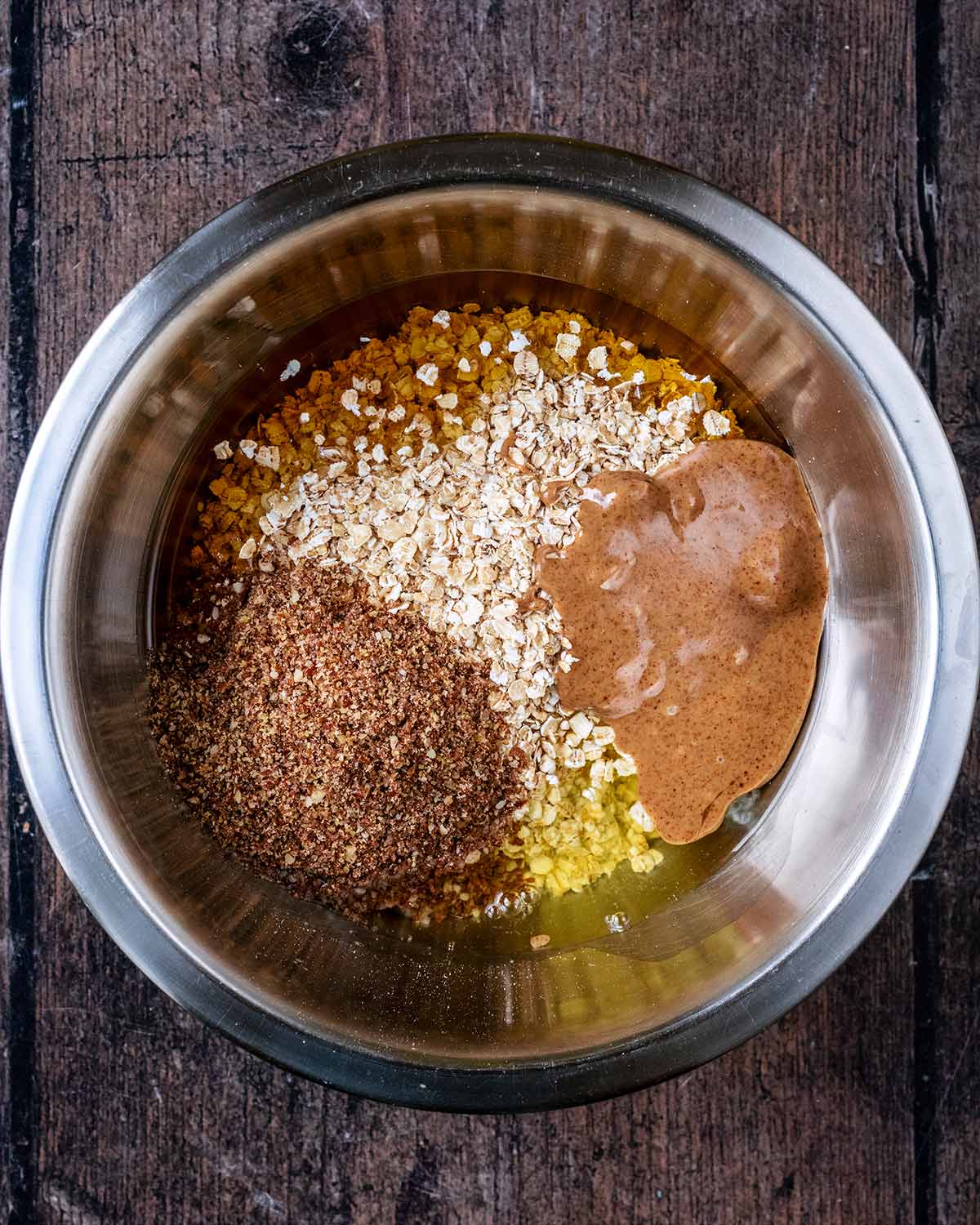 A mixing bowl containing oats, ground seeds, nut butter and egg white.