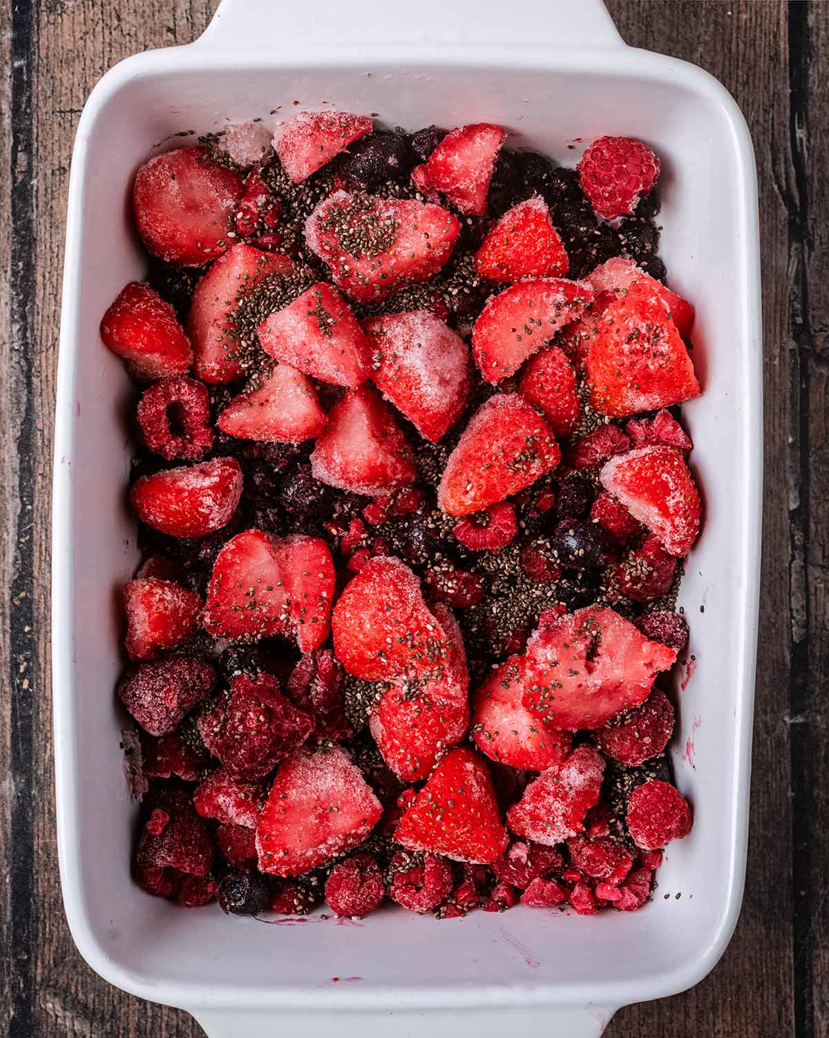 A baking dish containing frozen berries and chia seeds.