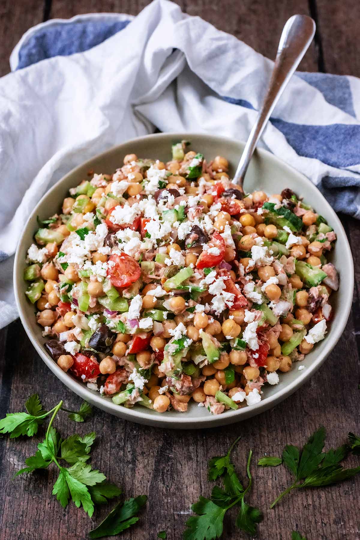 A bowl of tuna chickpea salad in front of a striped towel.