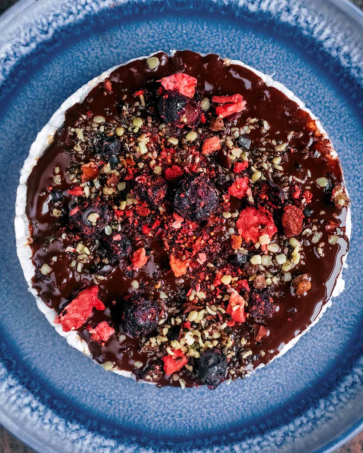 Melted chocolate spread over a rice cake then seeds and berries added.