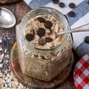 A jar of cookie dough overnight oats with a spoon in it.