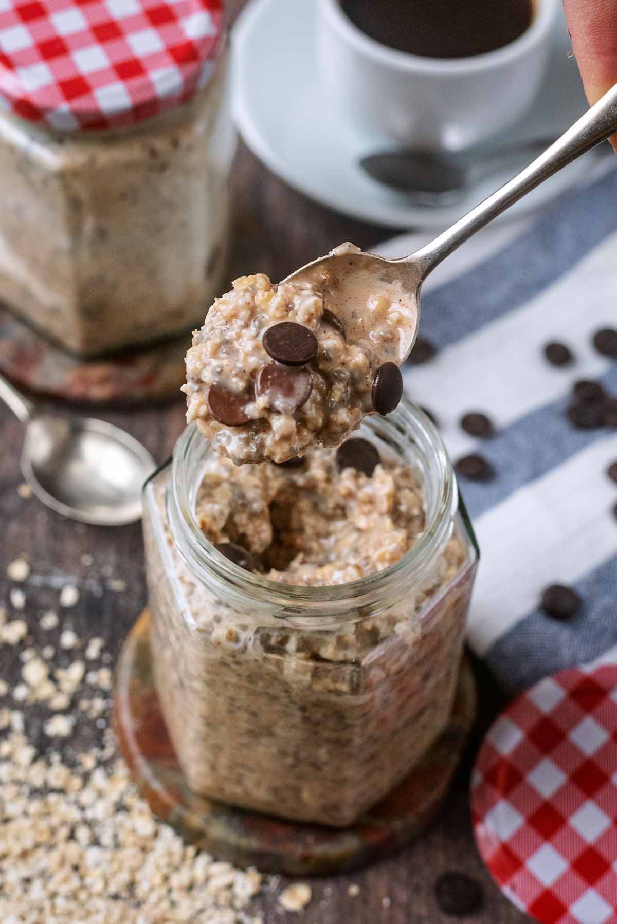 A spoon lifting some overnight oats out of a mason jar.