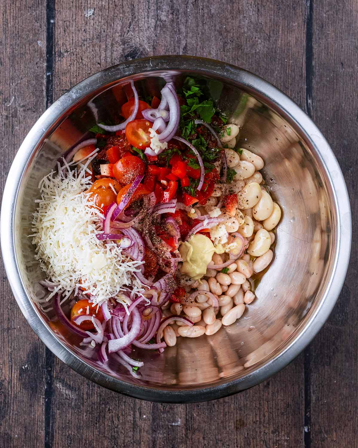 Chopped salad and herbs  in a large mixing bowl with white beans.