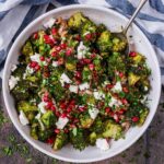 A large bowl of roasted broccoli salad with a serving spoon in it.