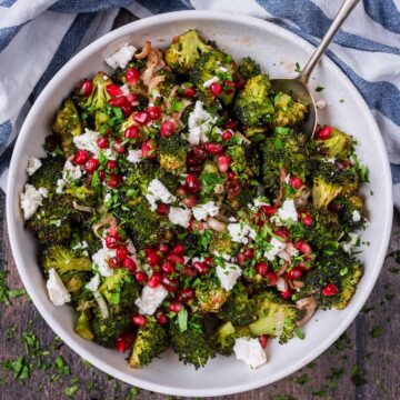 A large bowl of roasted broccoli salad with a serving spoon in it.