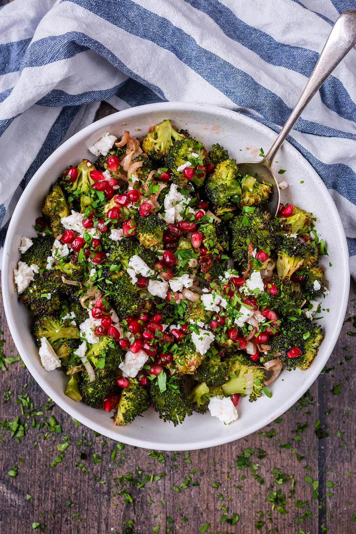 A bowl of broccoli salad next to a blue and white striped towel.