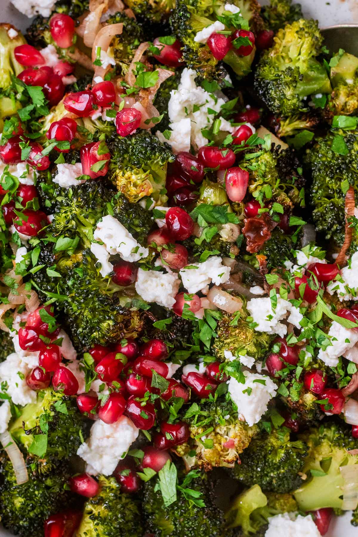 Cooked broccoli florets topped with pomegranate seeds and crumbled feta.