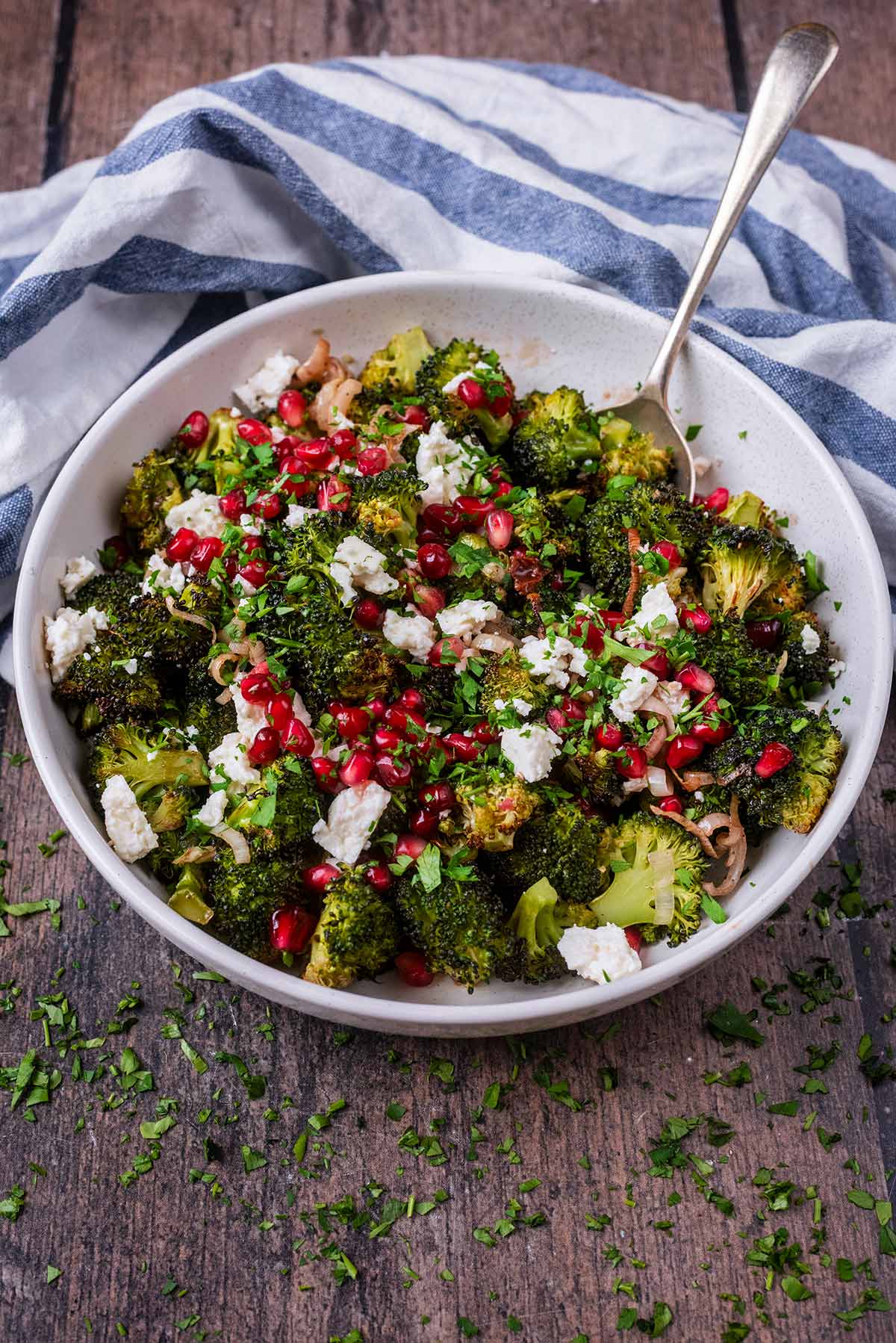 A bowl of broccoli salad in front of a striped tea towel.