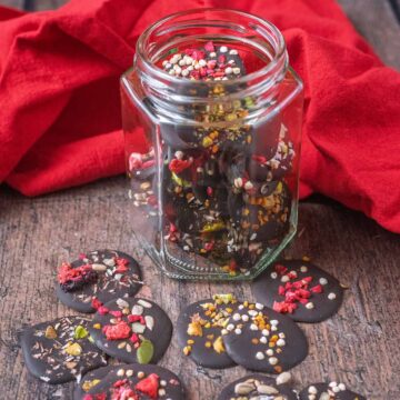 A jar of homemade chocolate buttons with more buttons scattered around it.