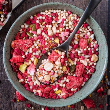 A small bowl of superfood sprinkles with a black spoon in it.