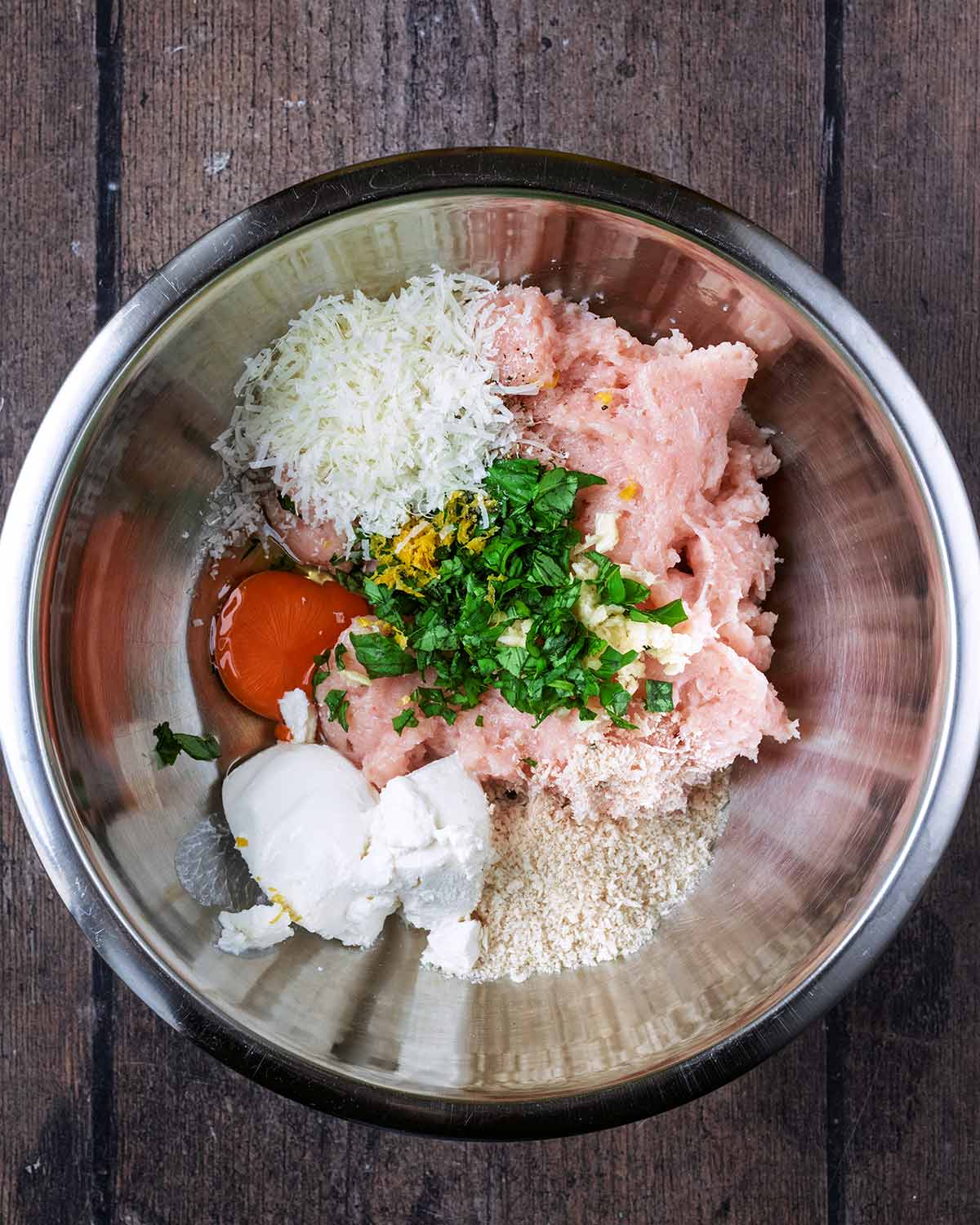 Ground chicken, ricotta cheese, breadcrumbs and herbs in a mixing bowl.