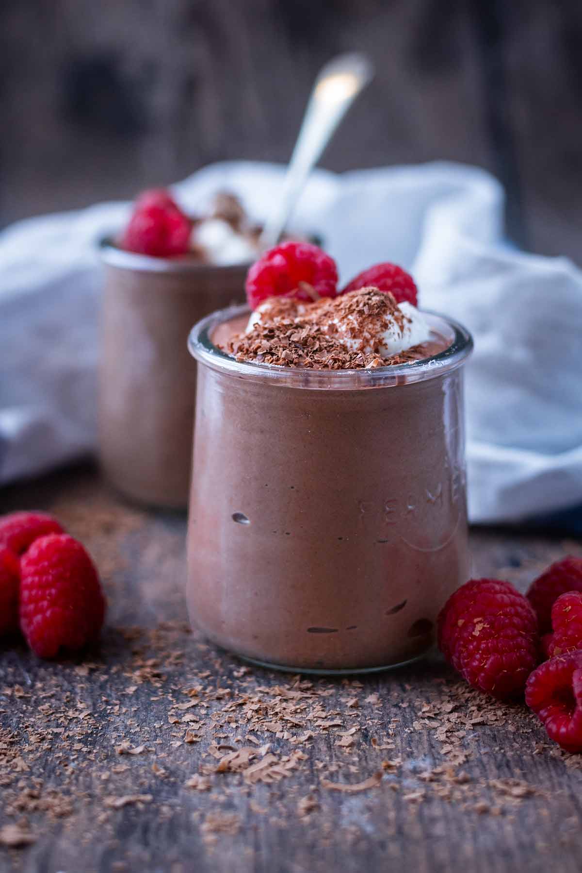 A pot of chocolate pudding with another chocolate pot in the background.