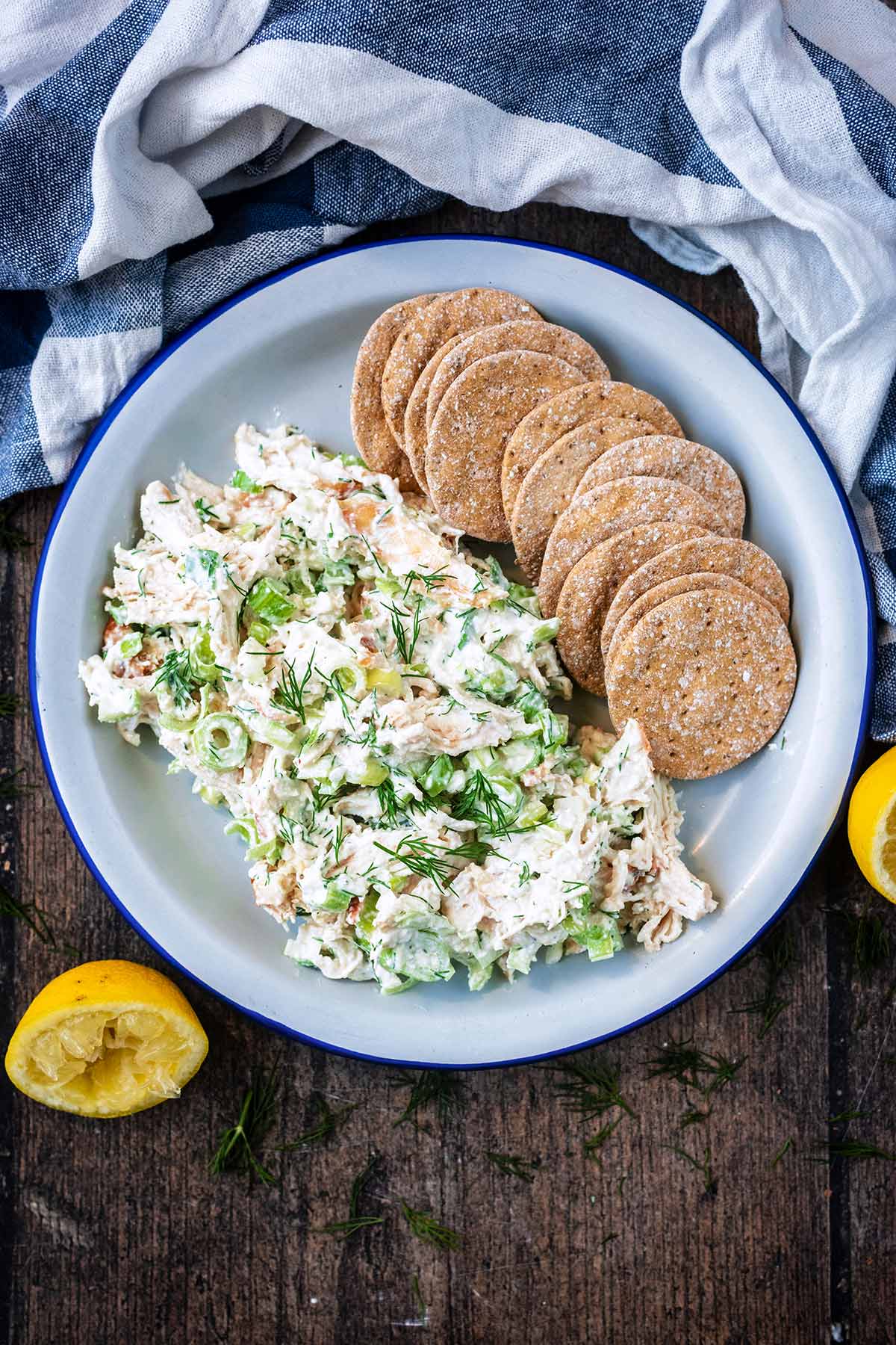 A plate of creamy chicken salad and crackers next to a striped towel.