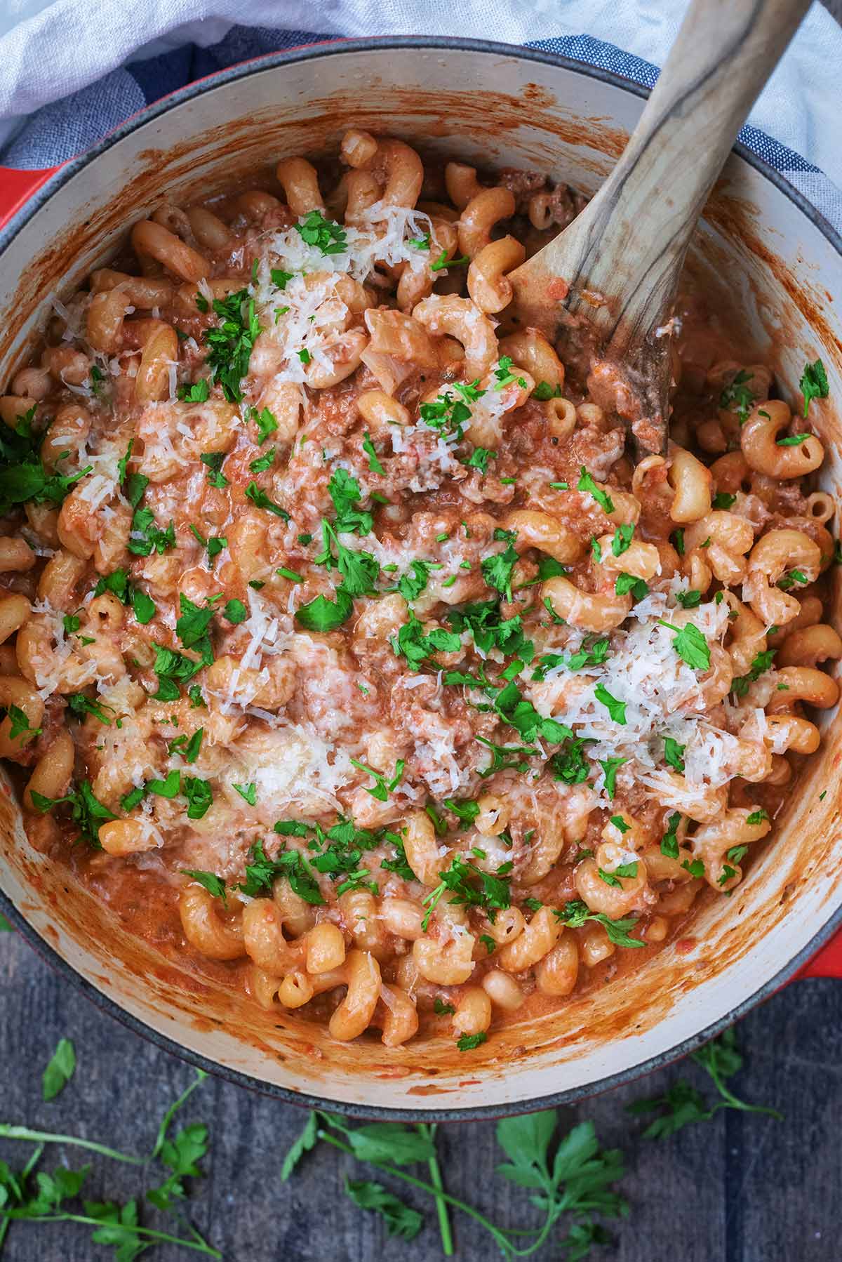 Beef pasta in a large cooking pot with a wooden spoon in it.