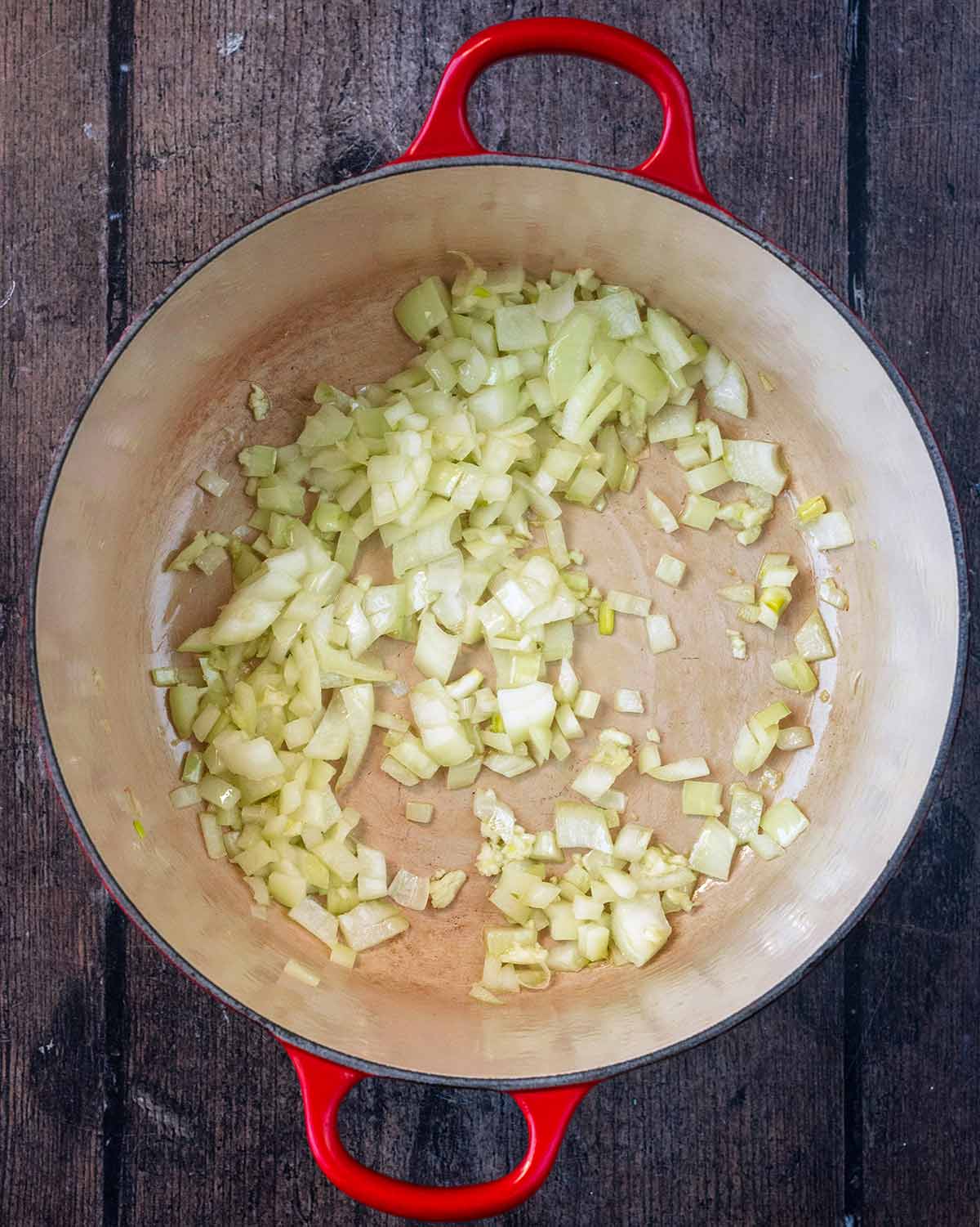 Chopped onions and crushed garlic cooking in oil in a large pan.