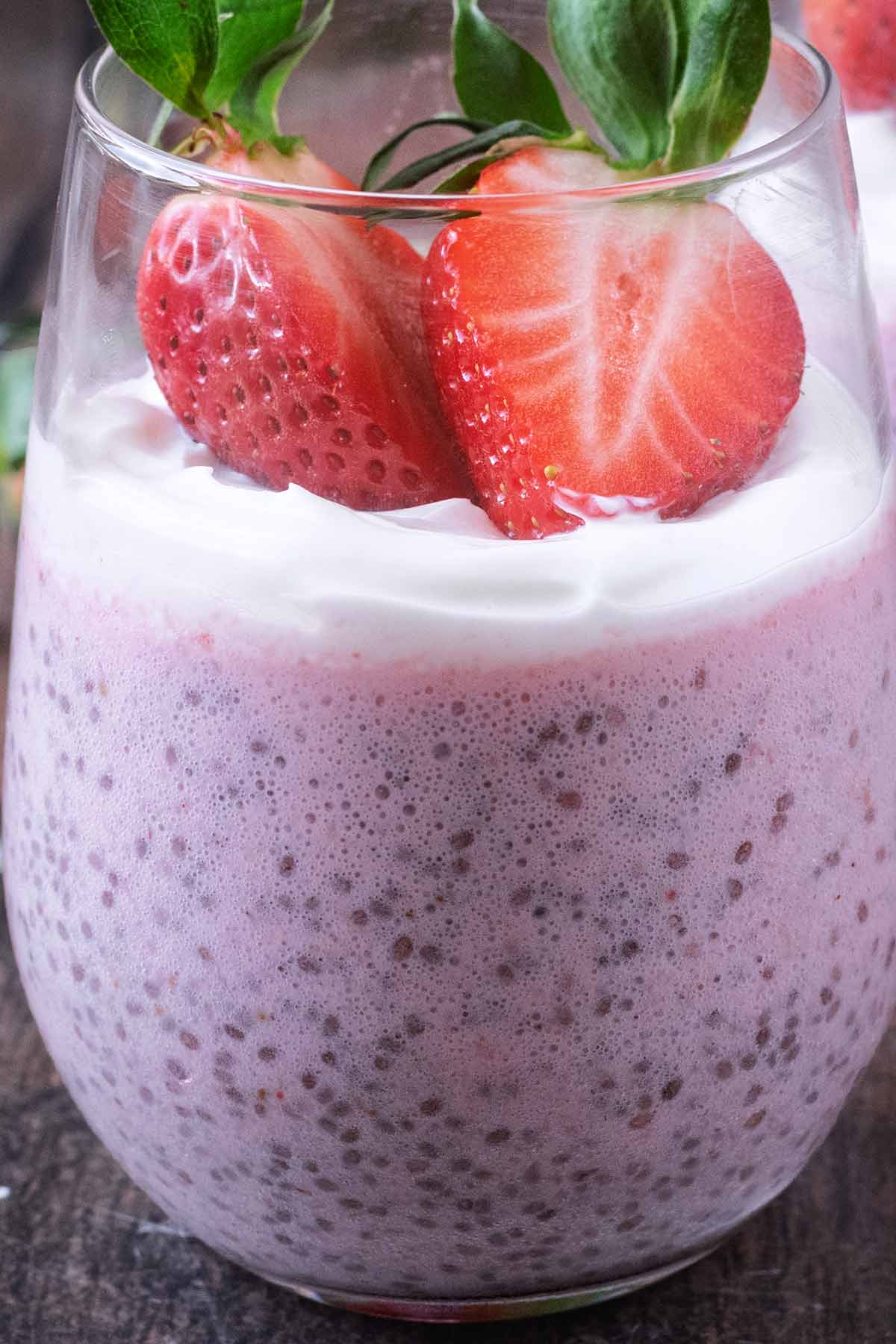 Chia pudding topped with a thin layer of yogurt and two strawberry halves.