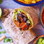 Bean Burrito surrounded by salsa, chips, guacamole and coriander leaves