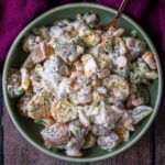 A bowl of high protein potato salad with a serving spoon in it.