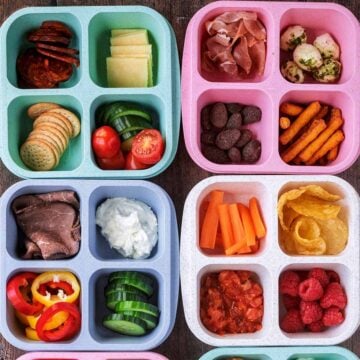 Four four-compartment snack boxes containing various vegetables, fruits, crackers and dips.