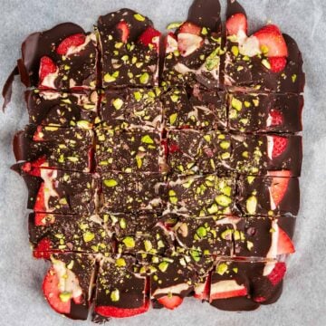 Chocolate Yogurt Strawberry Bark cut into squares on a sheet of parchment paper.