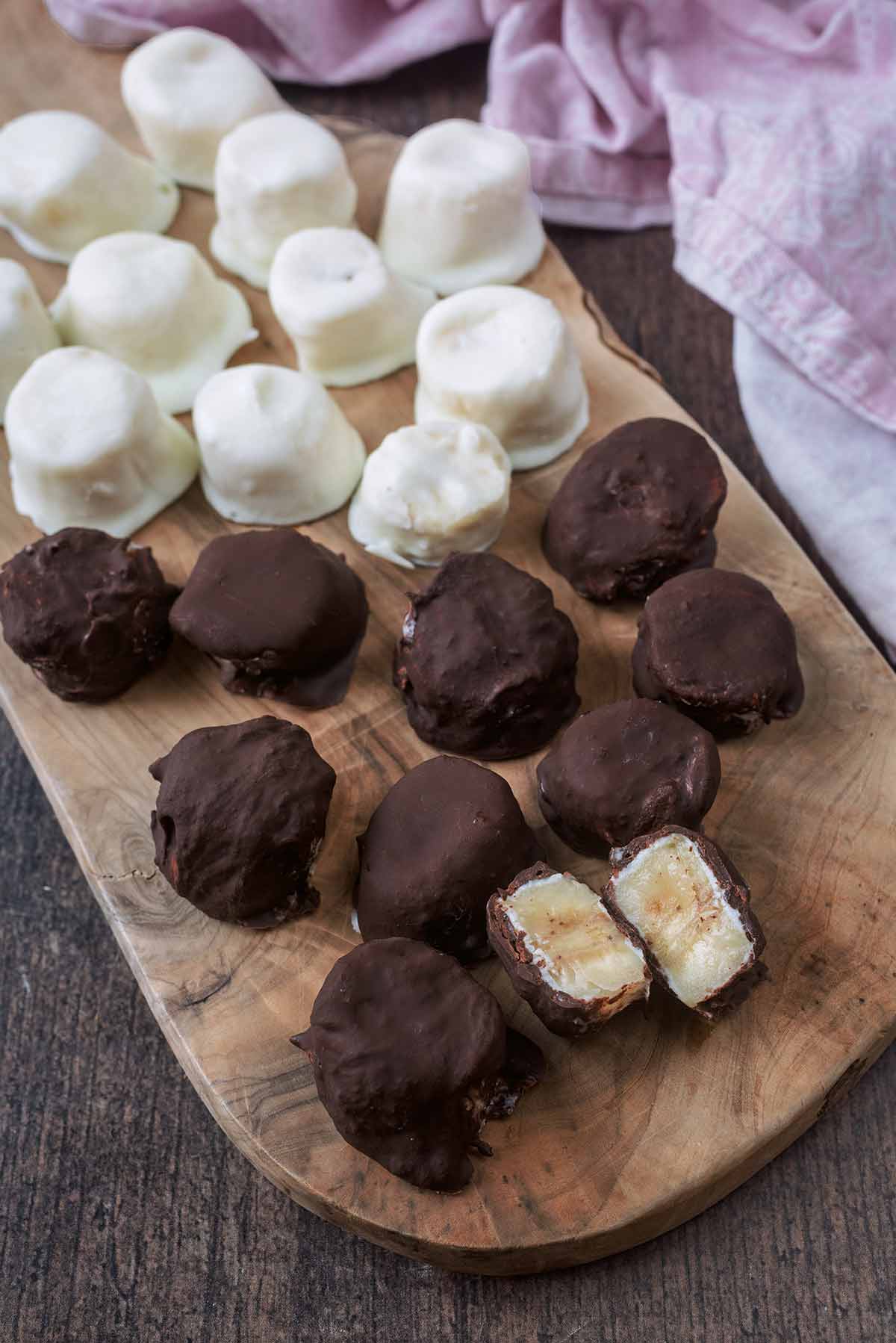 Chocolate covered banana slices and yogurt covered banana slices on a wooden serving board.