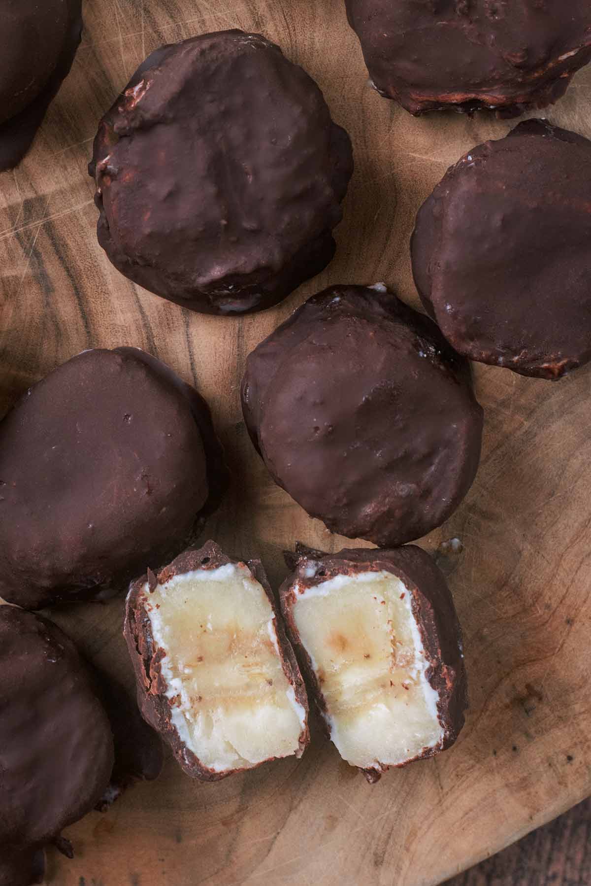 A chocolate and yogurt covered banana slice that has been cut in half, revealing the inside.